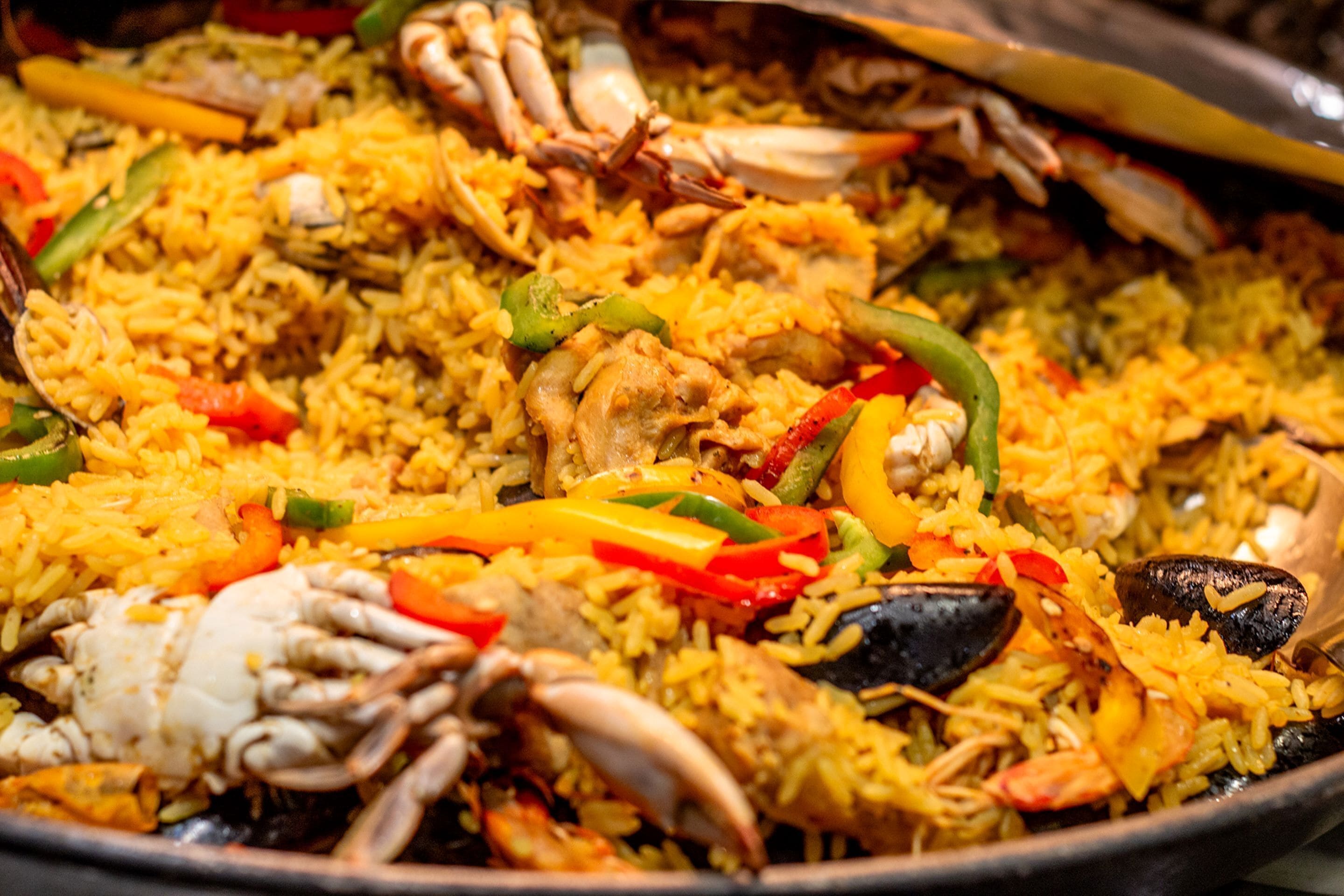 Primer plano de un plato de paella de mariscos, con arroz, camarones, mejillones y verduras.