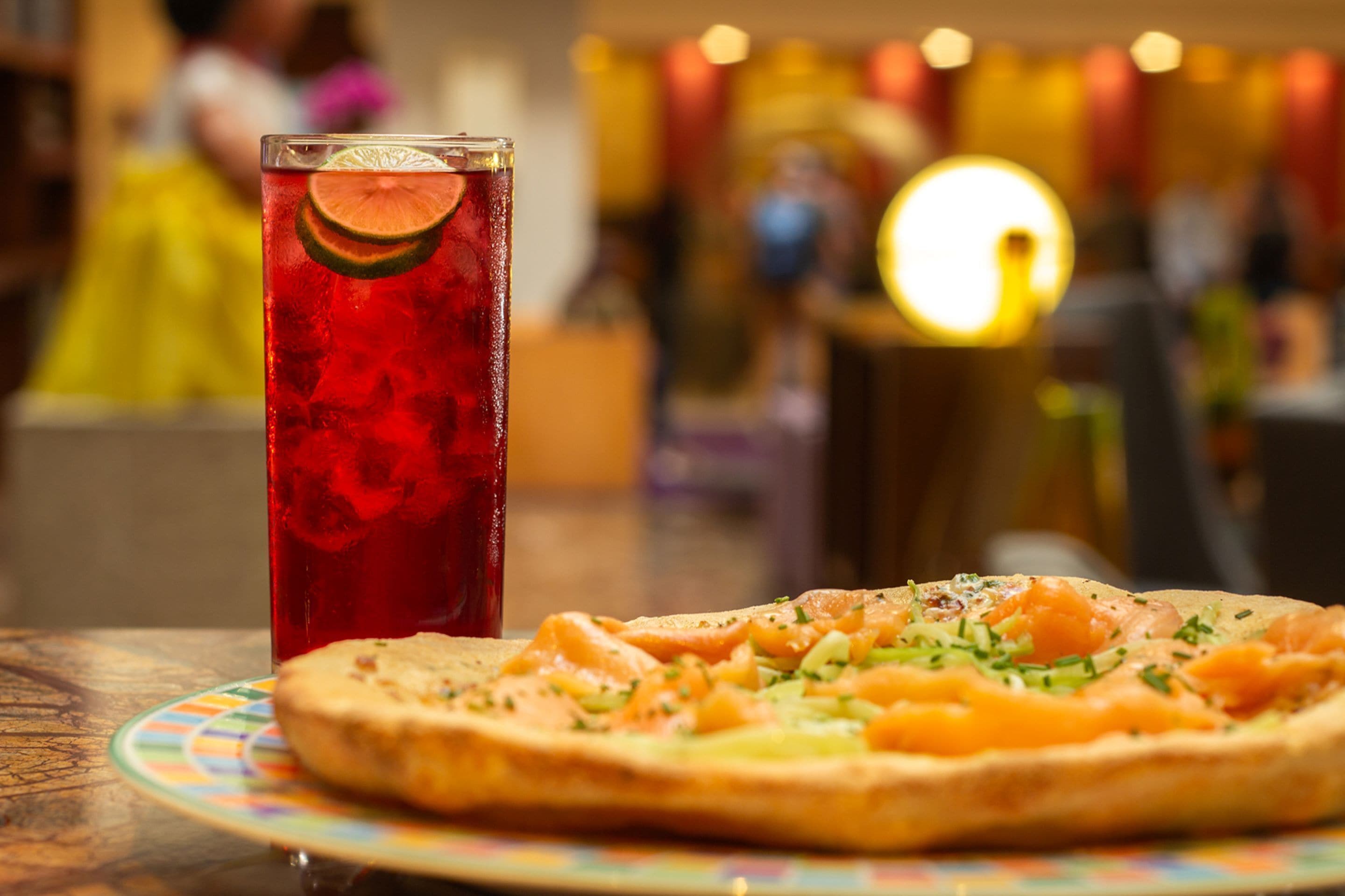 Une table avec une assiette de nourriture et un verre d’une boisson rouge.
