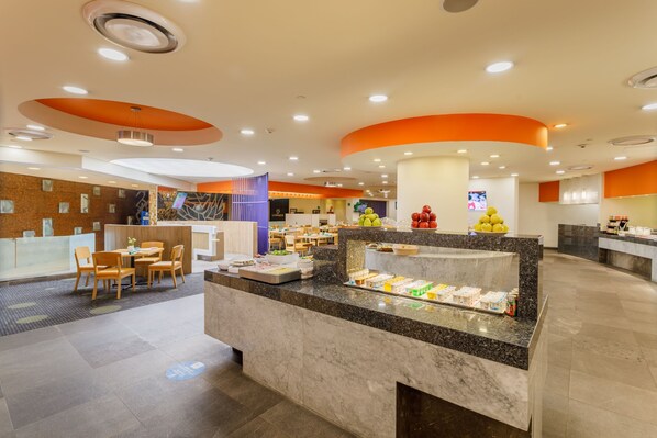 Un moderno hall de hotel con una recepción de mármol, zona de estar y un mostrador para desayunos.