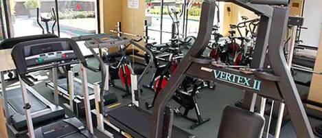 Une salle de sport équipée de divers appareils d’exercice, notamment des tapis de course, des vélos d’appartement et des appareils de musculation.