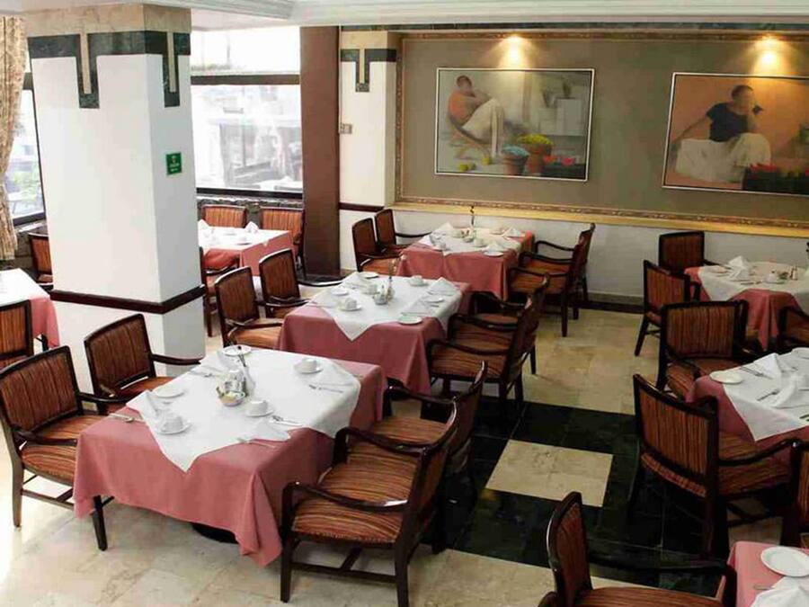 A dining area with tables set for service, chairs, and a checkered floor.