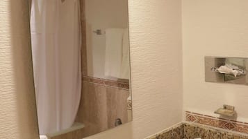 Une salle de bain avec un comptoir en granit, un lavabo, un miroir et un rideau de douche.