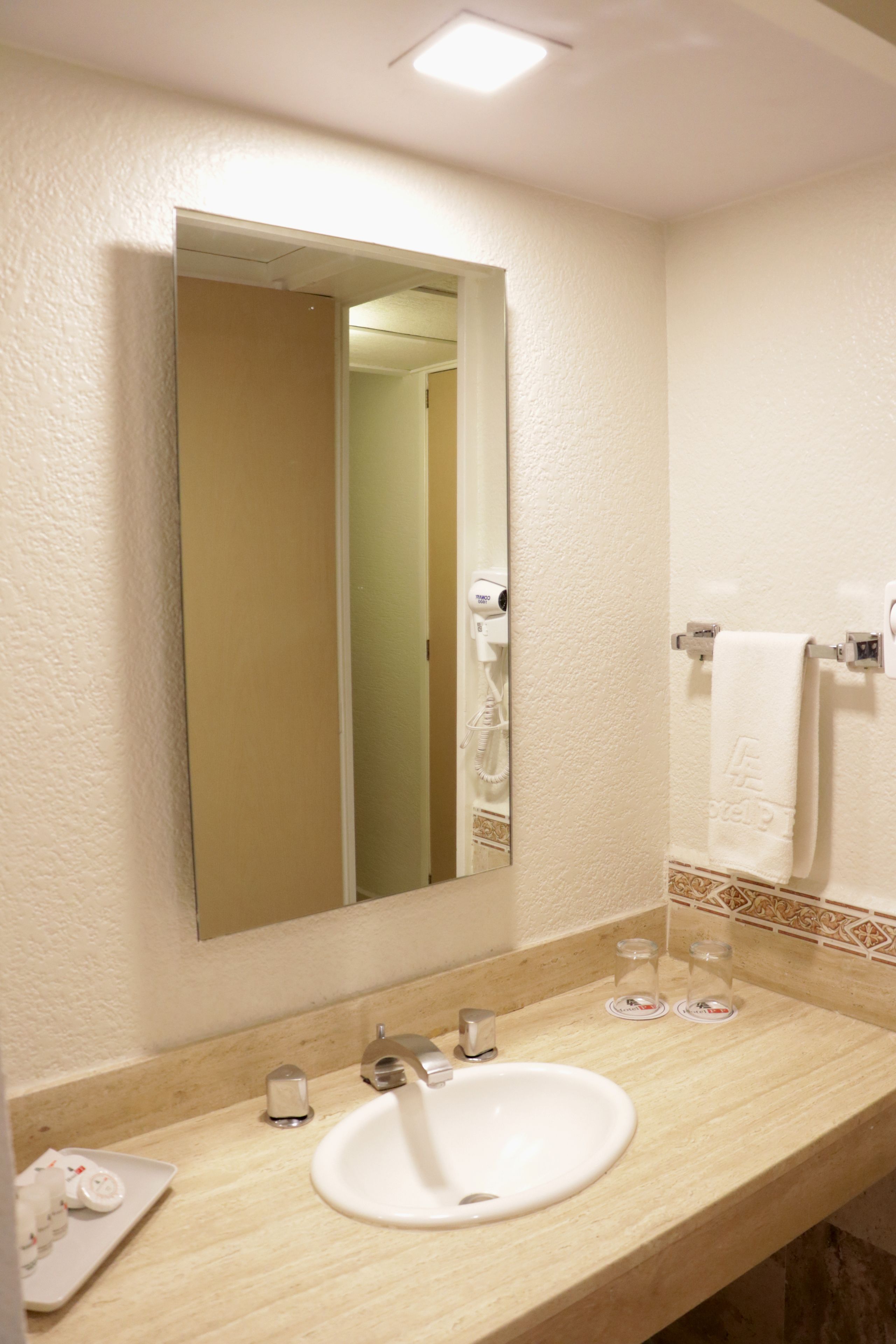 A bathroom with a white sink, a mirror, and a towel rack.