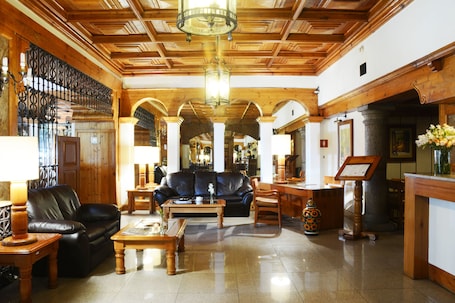 A lobby with a leather sofa, wooden coffee table, and a reception desk.