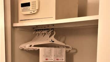 Un armario de hotel con un organizador colgante blanco, un portaequipajes negro y un termostato digital en la pared.