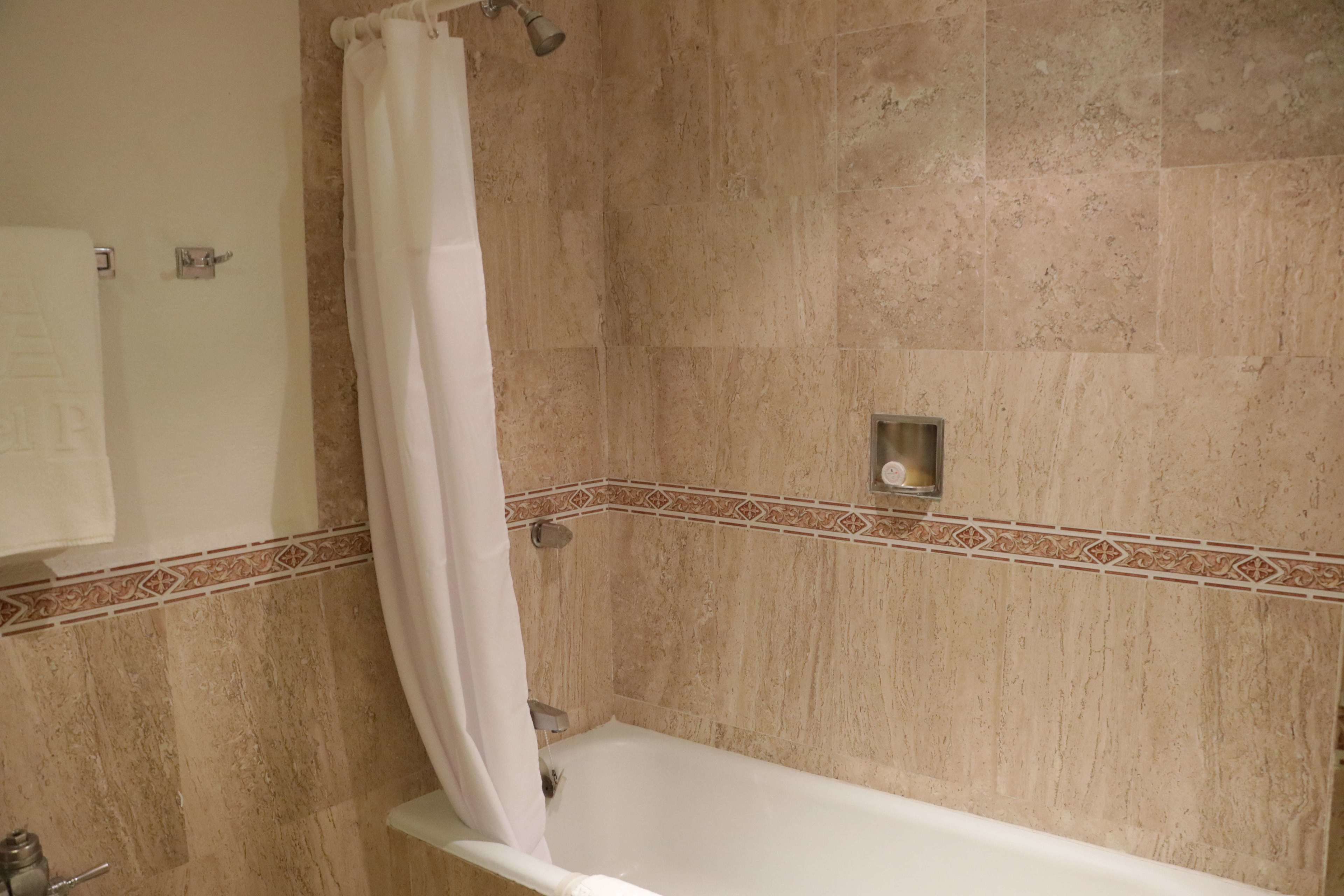 A bathroom with a bathtub, a shower curtain, and a tiled wall with a decorative border.