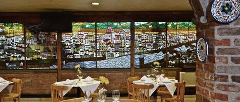 Un restaurante con paredes de ladrillo, ventanas de vitral y mesas dispuestas para comer.