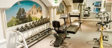 A gym with treadmills, stationary bikes, and dumbbells.