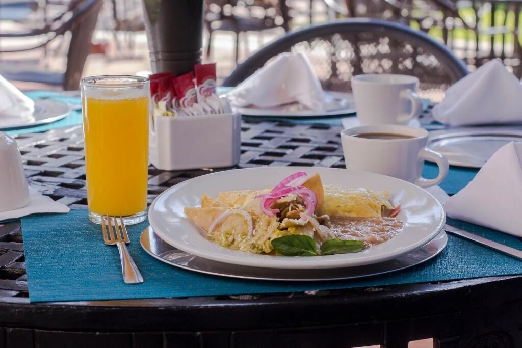 A table with a plate of food, a glass of orange juice, and a cup of coffee.