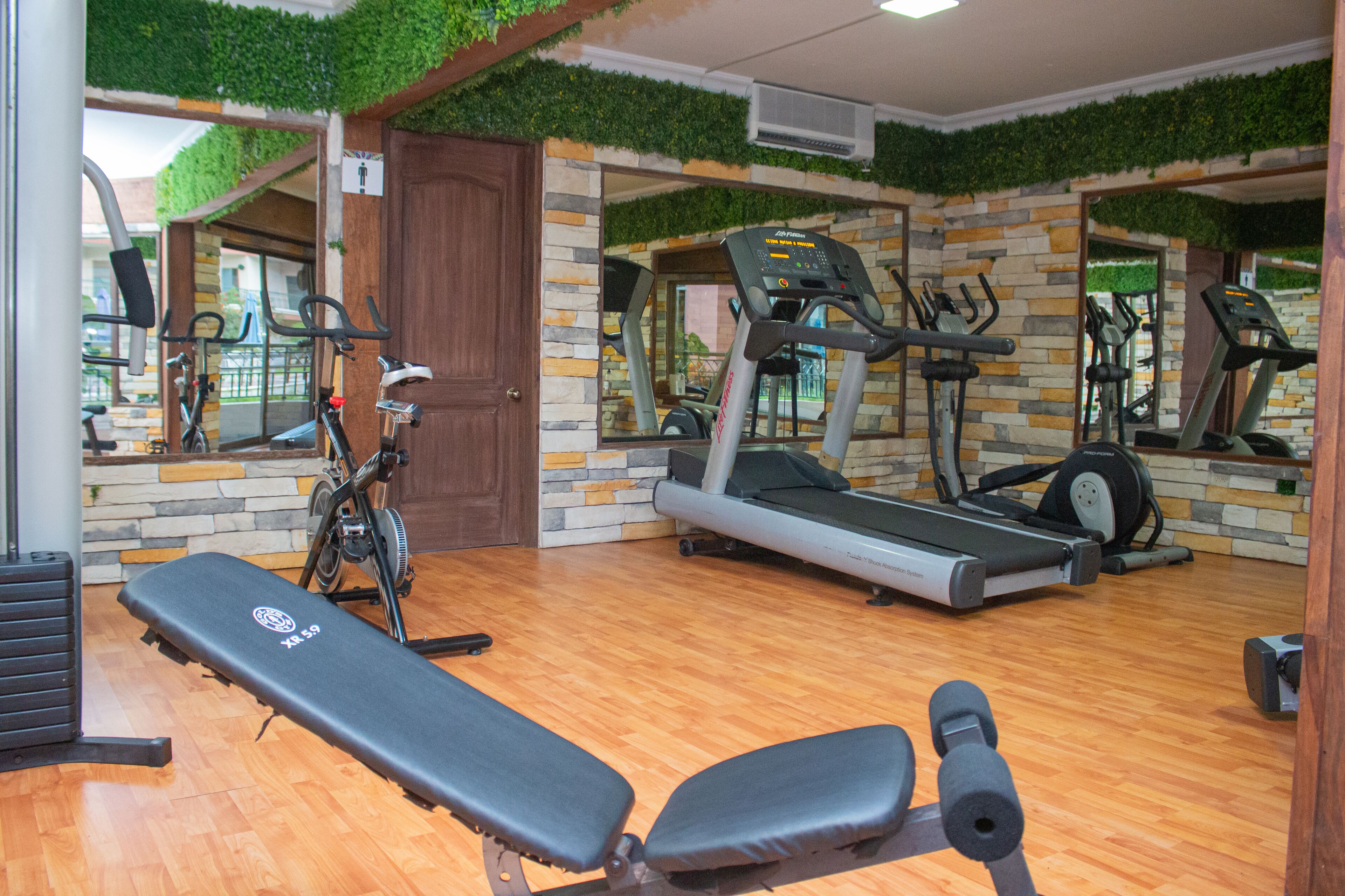 Un gimnasio con una banca, cintas de correr y bicicletas estáticas.