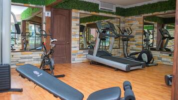 Un gimnasio con una banca, cintas de correr y bicicletas estáticas.