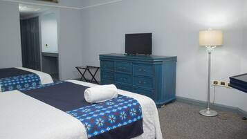 Una habitación de hotel con dos camas, un aparador azul, un televisor y una lámpara de pie.