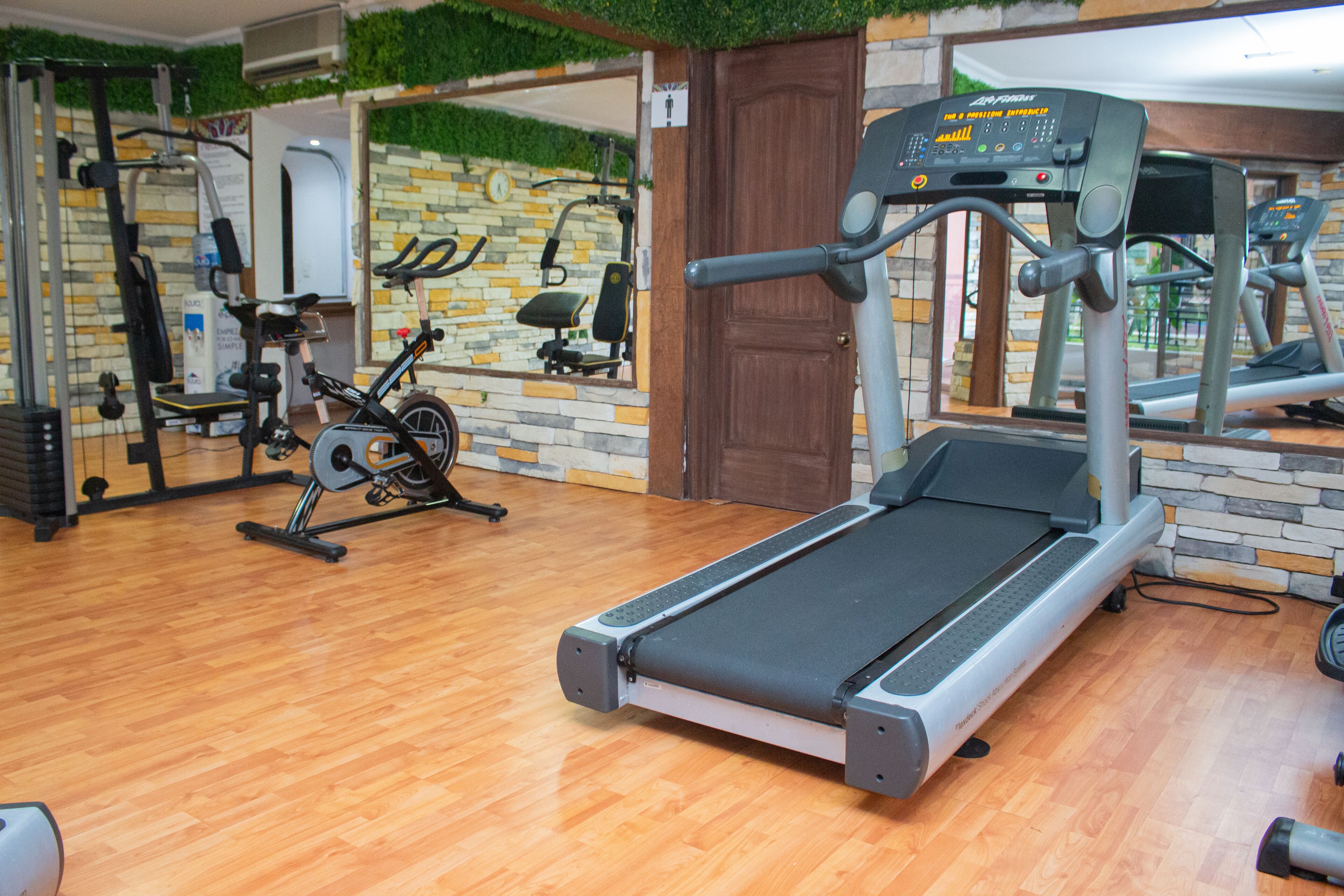 Un gimnasio con cinta de correr, bicicletas estáticas y diversas máquinas de ejercicio.