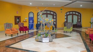 A lobby with a central decorative deer sculpture, multiple armchairs, and a 'No Tochar' sign.