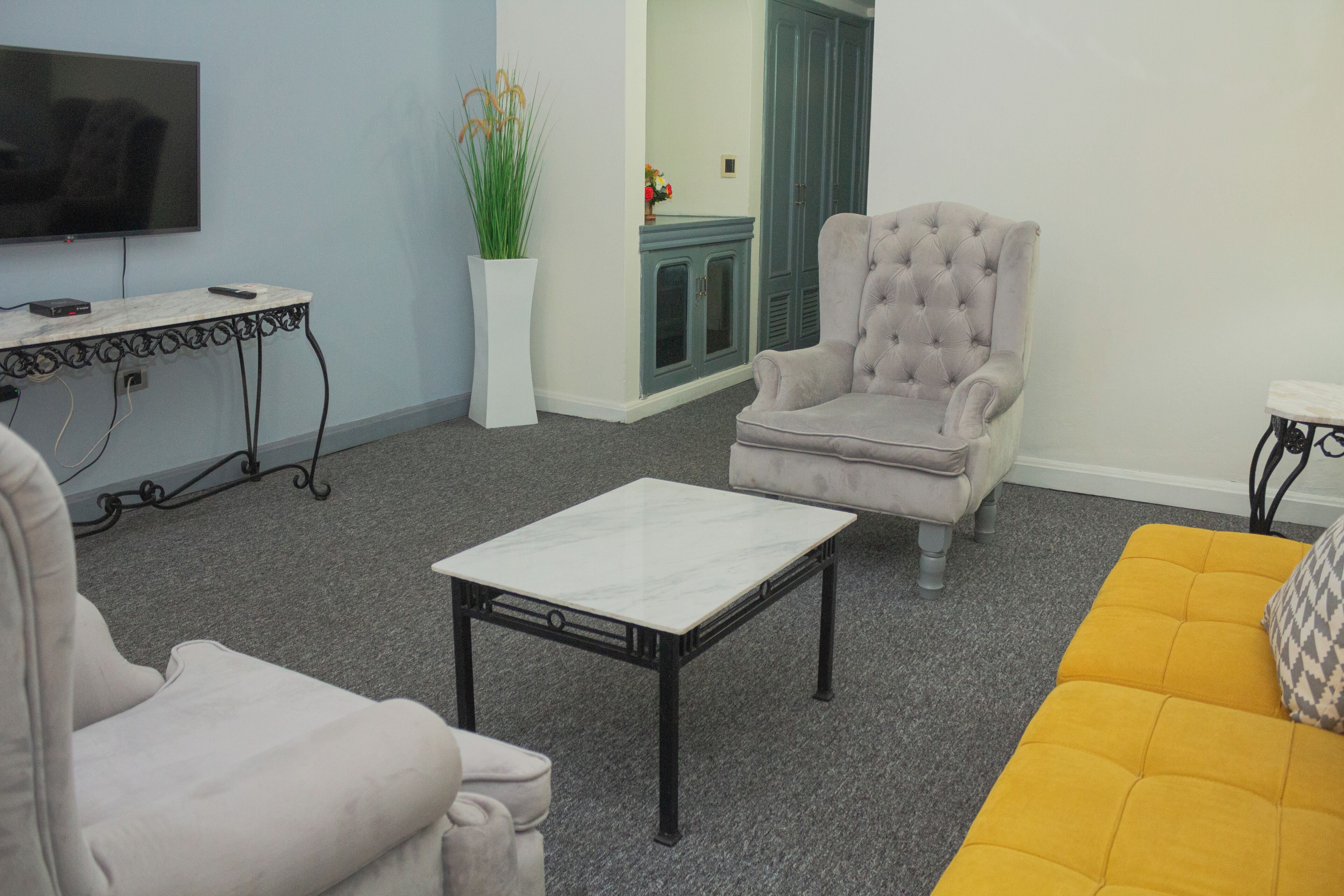 Una sala de estar con televisión, sofá, sillón, mesa de centro y aparador.