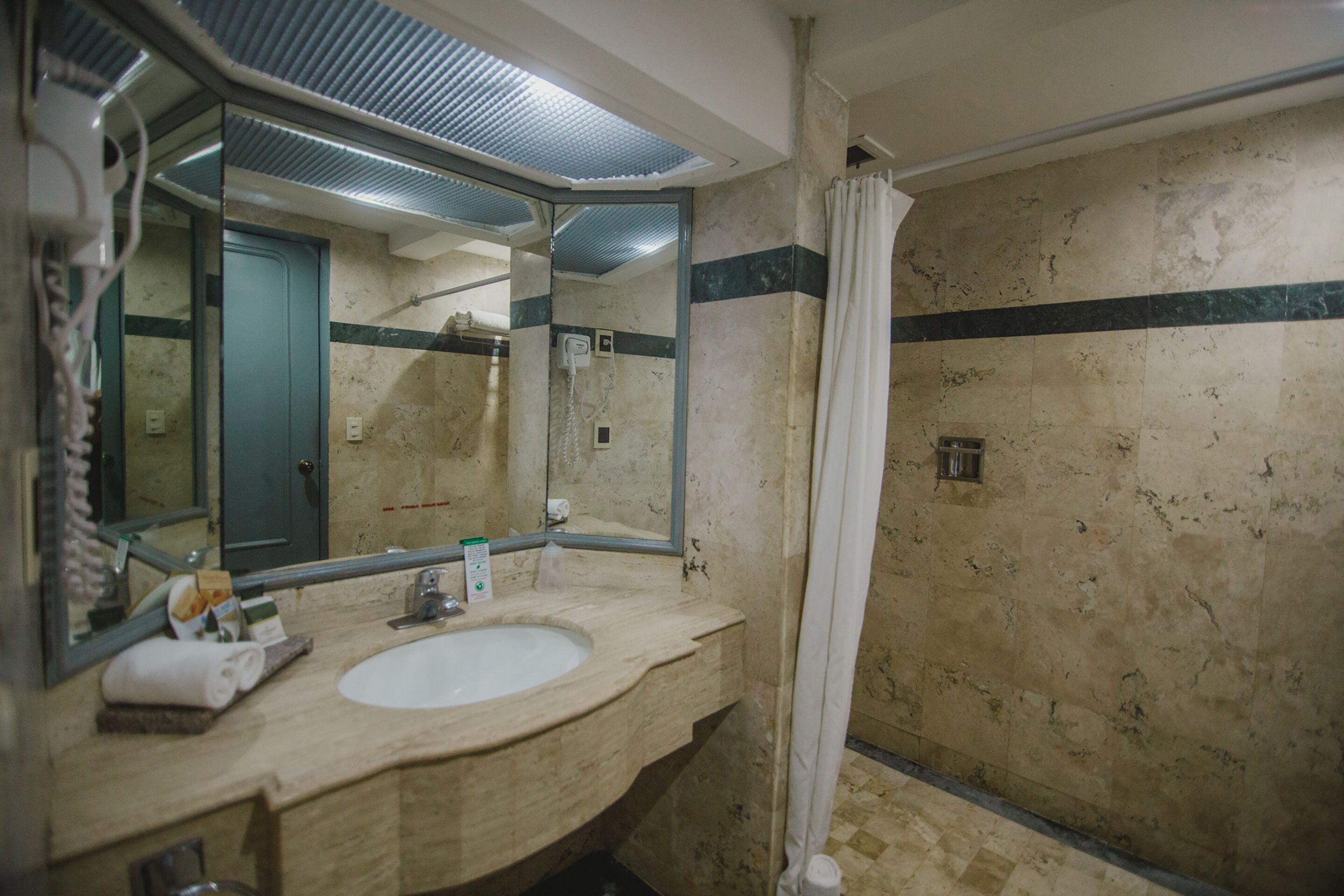 A bathroom with a sink, mirror, and shower curtain.