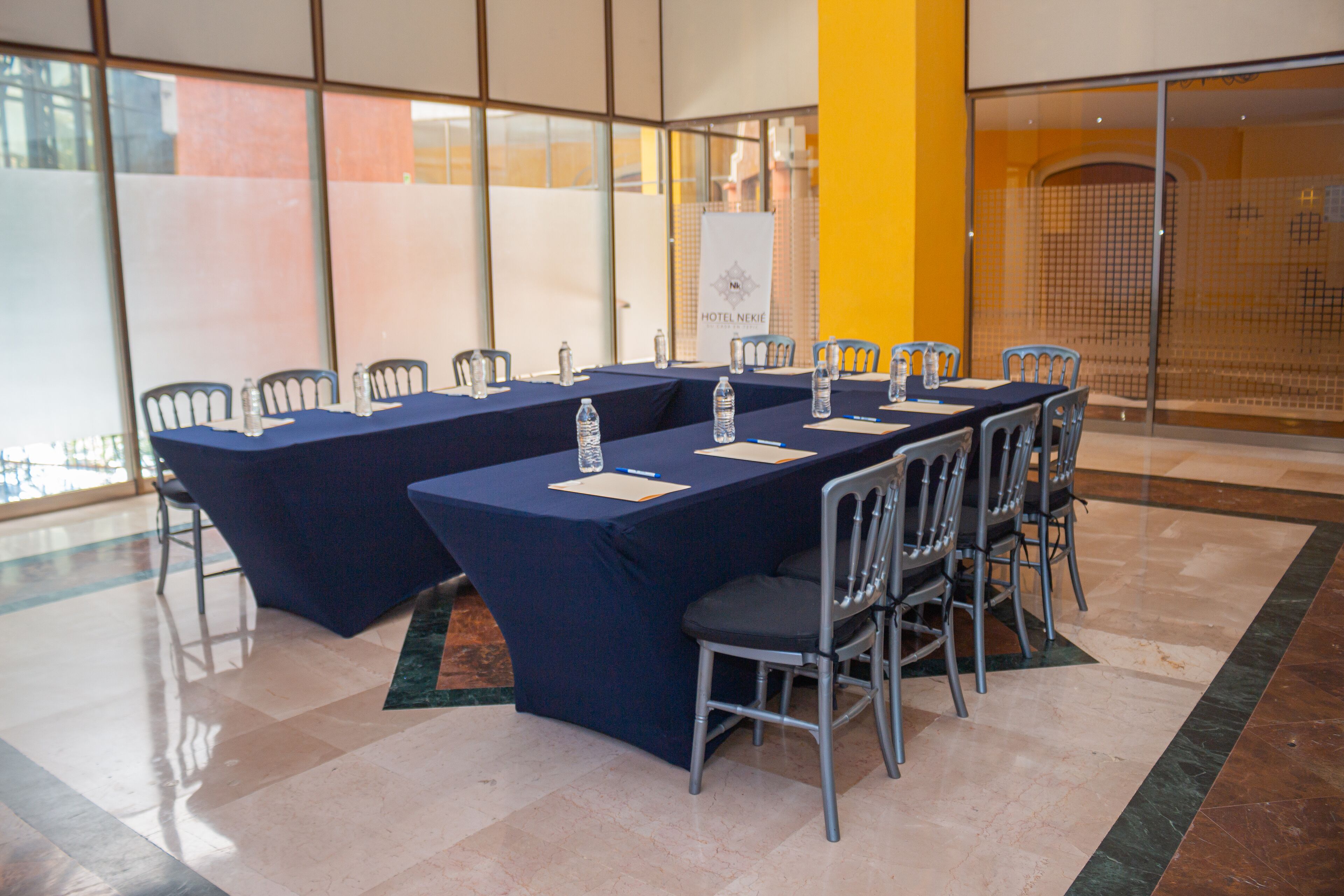 A conference room with a long table, chairs, water bottles, and a banner.