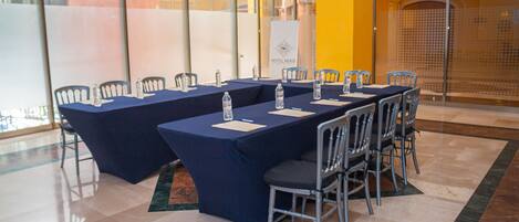 A conference room with a long table, chairs, water bottles, and a banner.