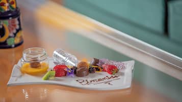 Une assiette de desserts, avec divers bonbons et fruits, est posée sur une table près d’une fenêtre.