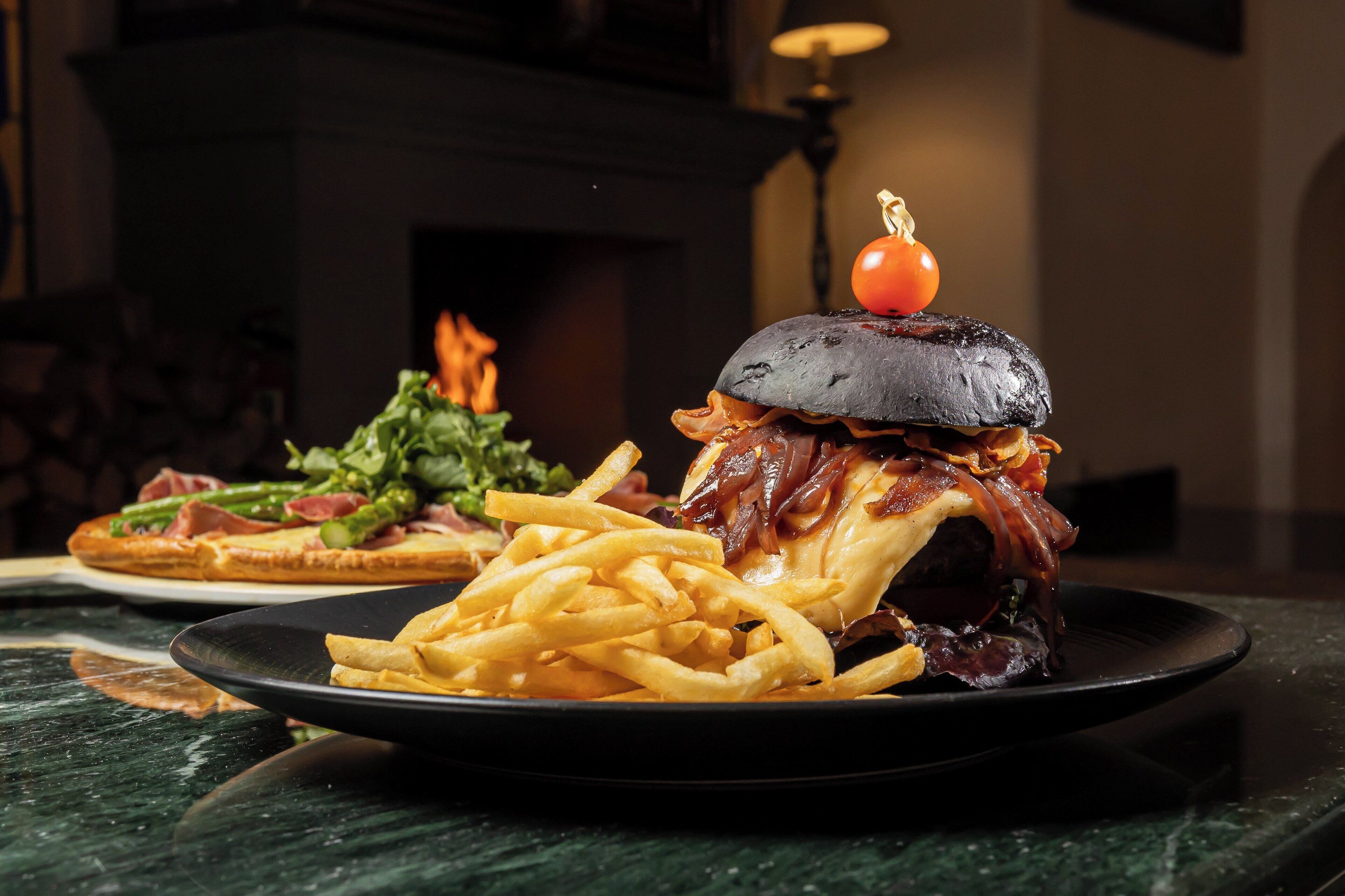 A plate of food with a burger and fries, and another plate with a salad and bread.