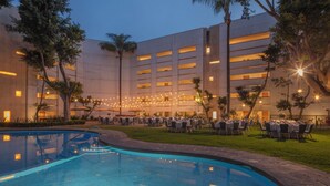 A hotel courtyard with a swimming pool, outdoor seating, and string lights. - InterContinental Presidente Puebla by IHG (Puebla)