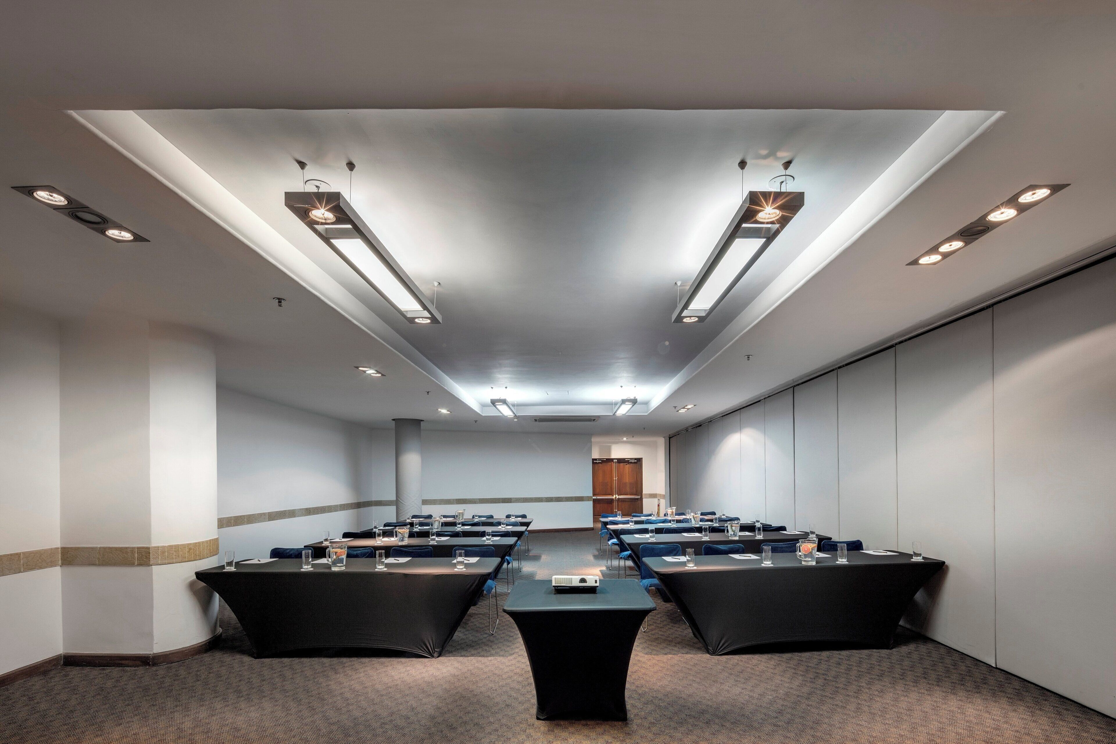 A conference room with a long table, chairs, and a projector.