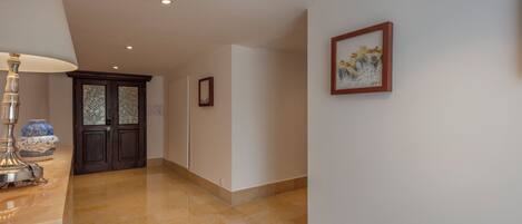Un pasillo con una lámpara, un jarrón y una puerta con paneles de vidrio.