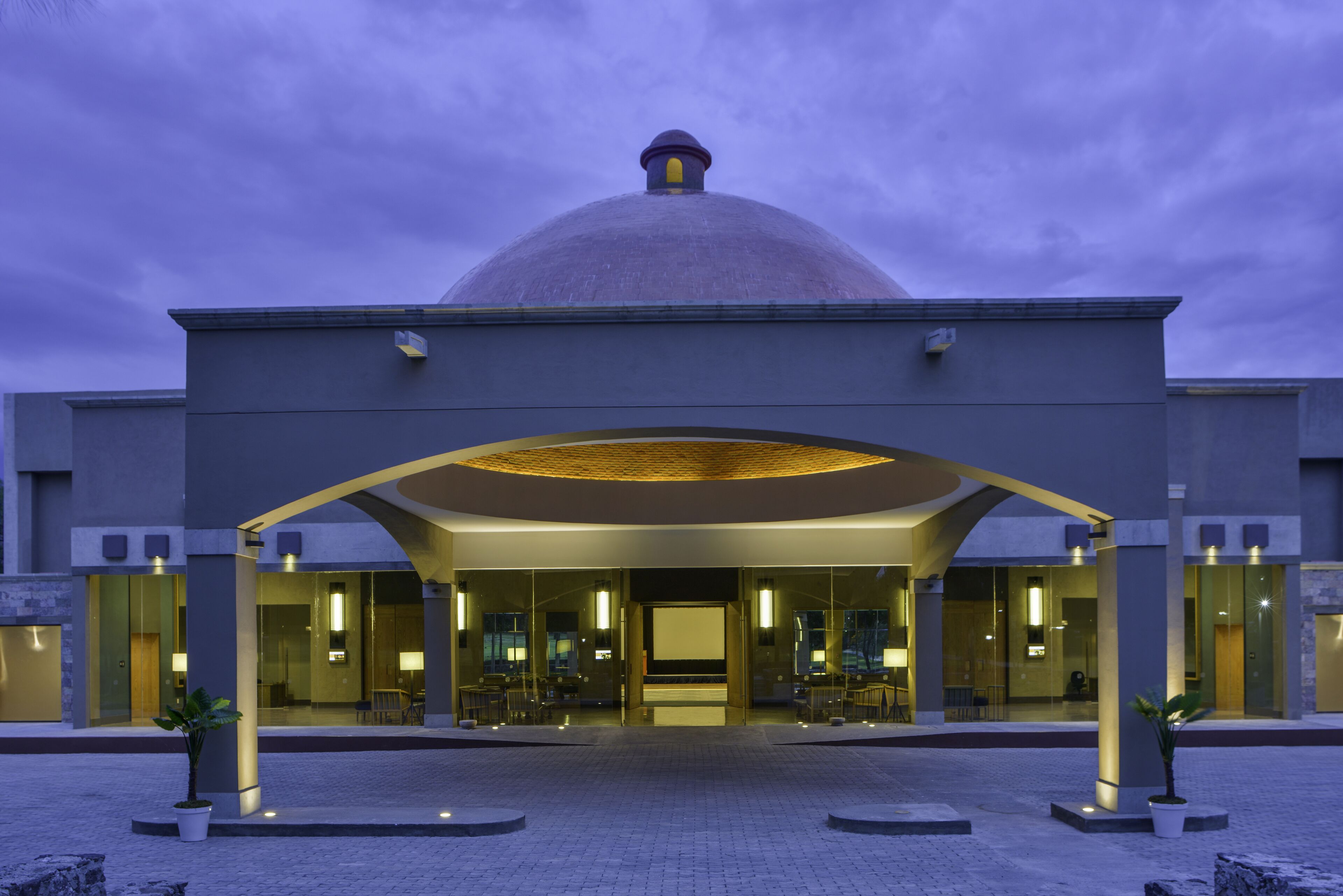 A modern hotel entrance with a large dome and a covered walkway.