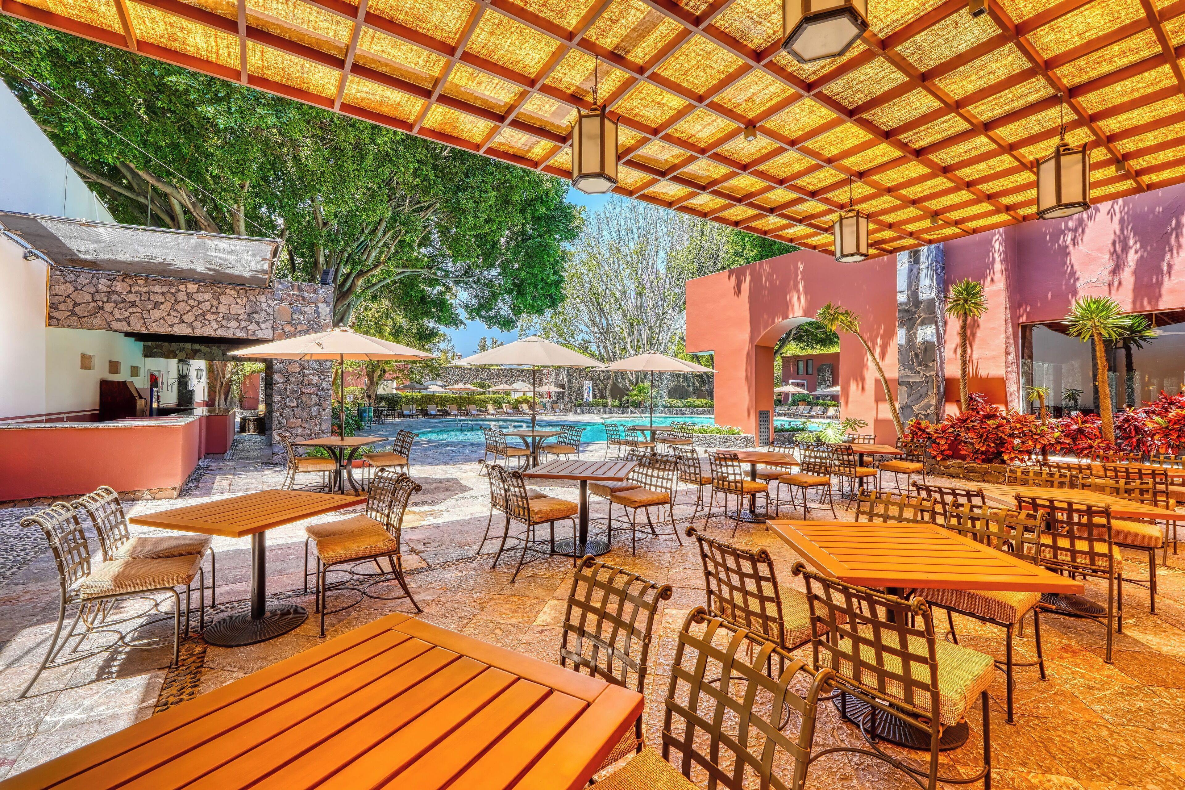 An outdoor patio area with tables and chairs, a pool, and a stone wall.