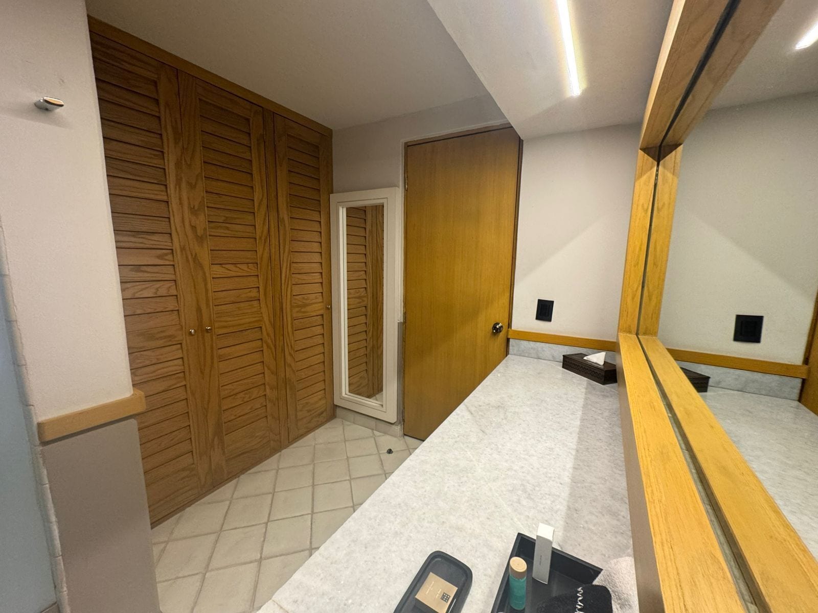 A bathroom with a wooden vanity, a mirror, a towel rack, and a toilet.
