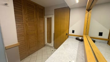 Un baño con tocador de madera, espejo, toallero y retrete.