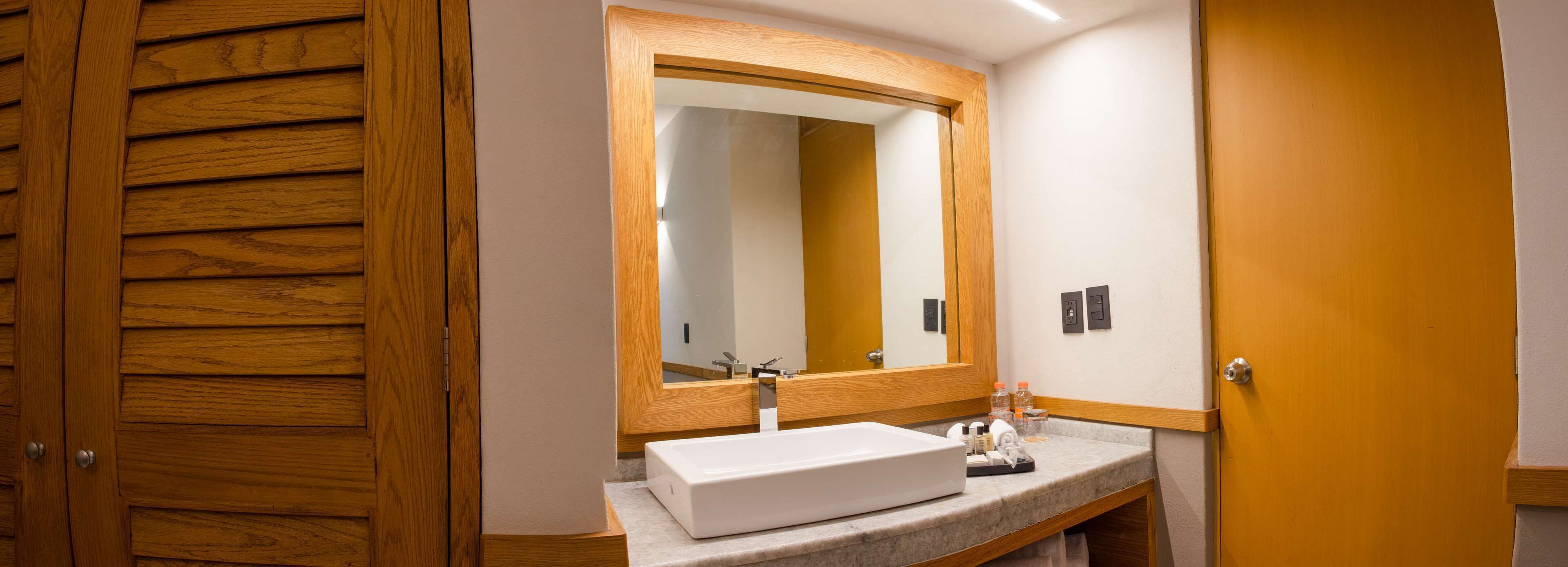 A bathroom with a wooden door, a white sink, and a large mirror.