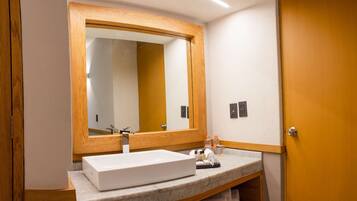 A bathroom with a wooden door, a white sink, and a large mirror.