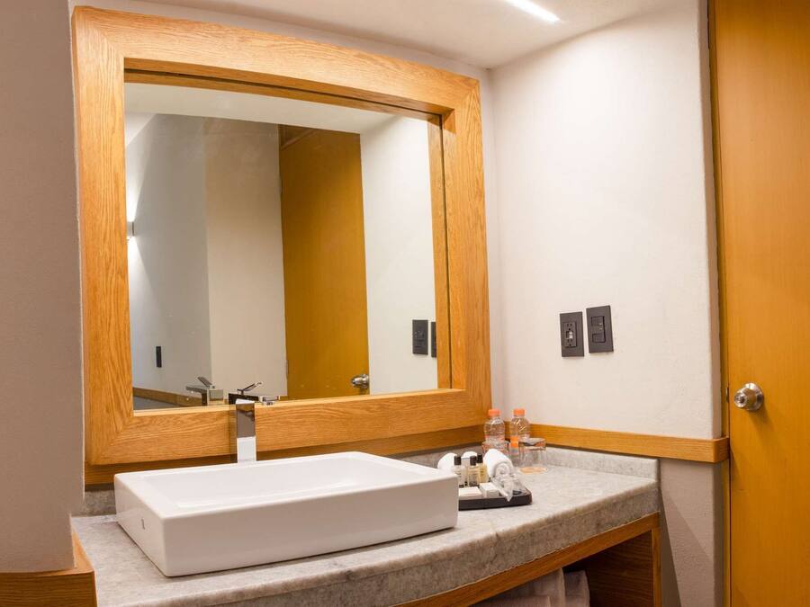 A bathroom with a wooden door, a white sink, and a large mirror.