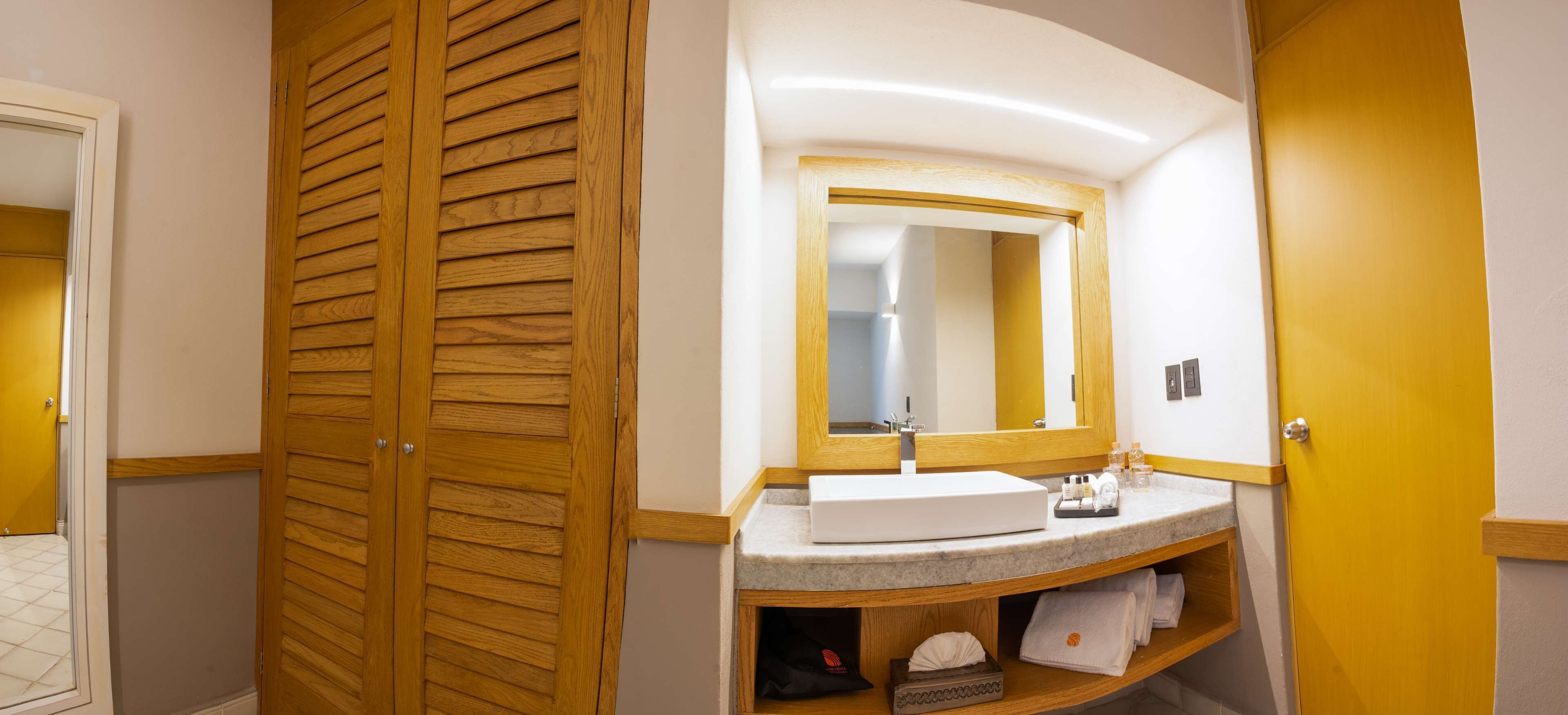 Ein Badezimmer mit Holztür, Waschbecken mit Spiegel und Handtuchhalter.