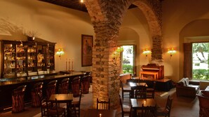 A bar area with a stone column, wooden furniture, and a piano. - Hacienda Jurica by Brisas (Querétaro)