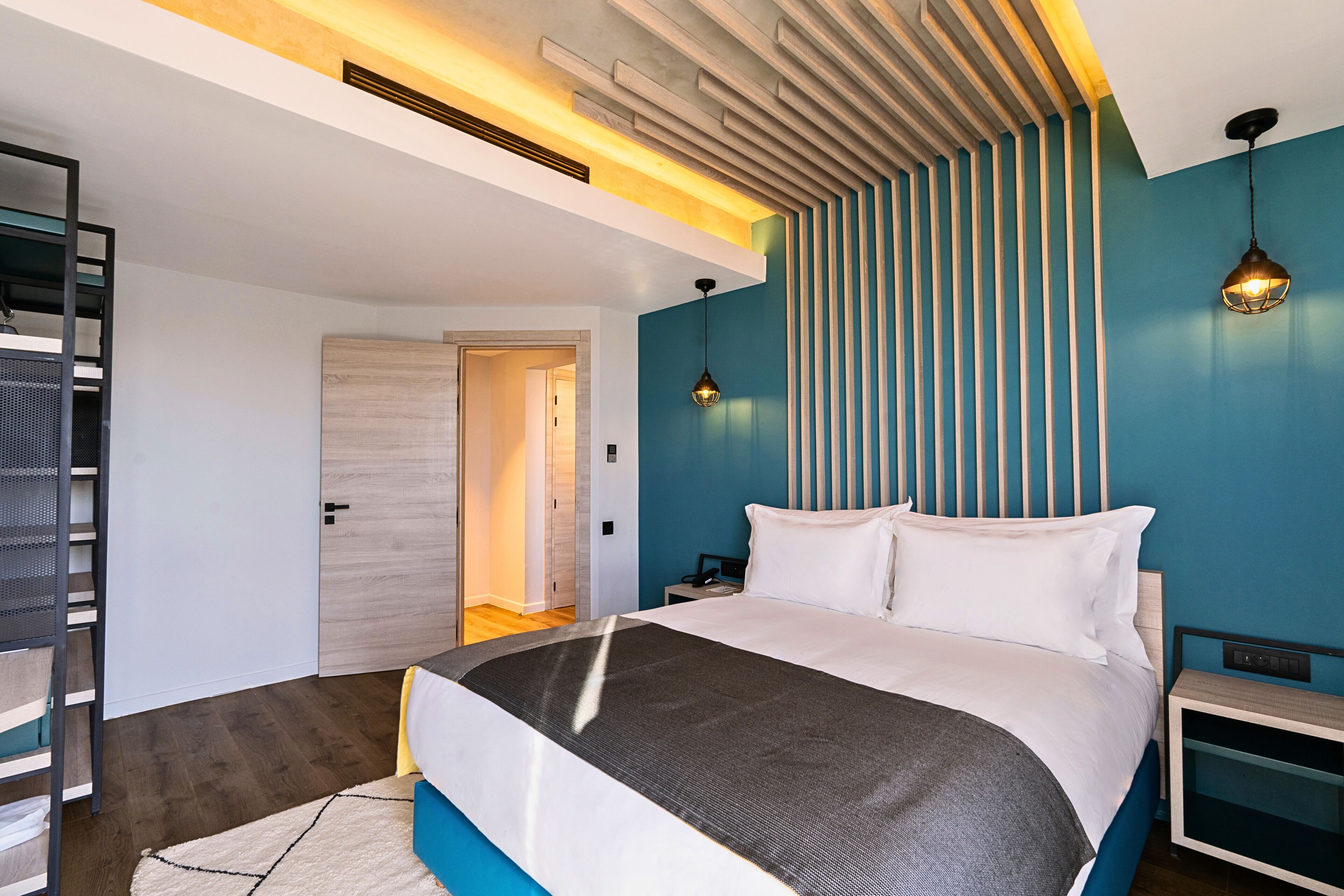 Un dormitorio moderno con una cama grande, una mesita de noche, una lámpara de pared y un diseño de listones de madera en la pared.