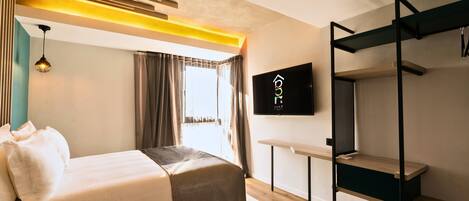 A modern hotel room with a bed, a TV mounted on the wall, a wooden bench, and a window with curtains.