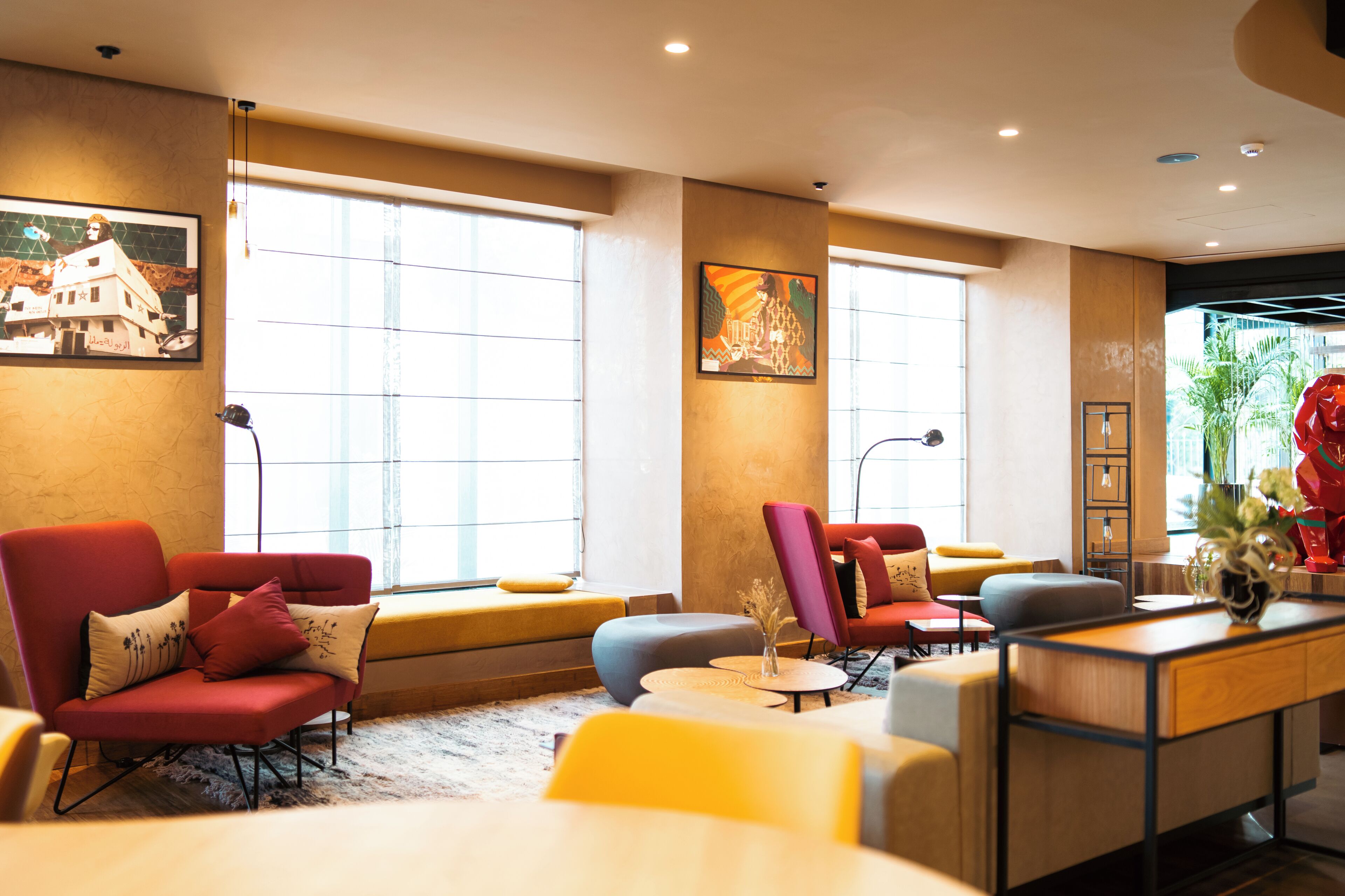 A modern hotel lobby with comfortable seating, large windows, and artwork on the walls.
