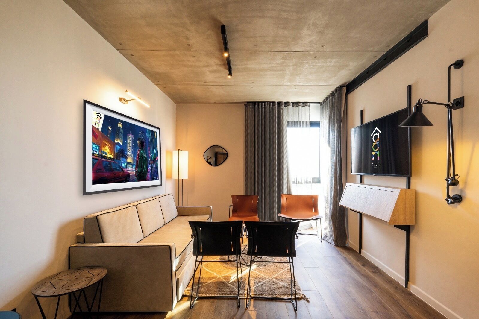 A modern hotel room with a sofa, chairs, a small table, a TV, and a painting on the wall.