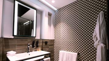A modern bathroom with a large mirror, a white sink, and a patterned wall.
