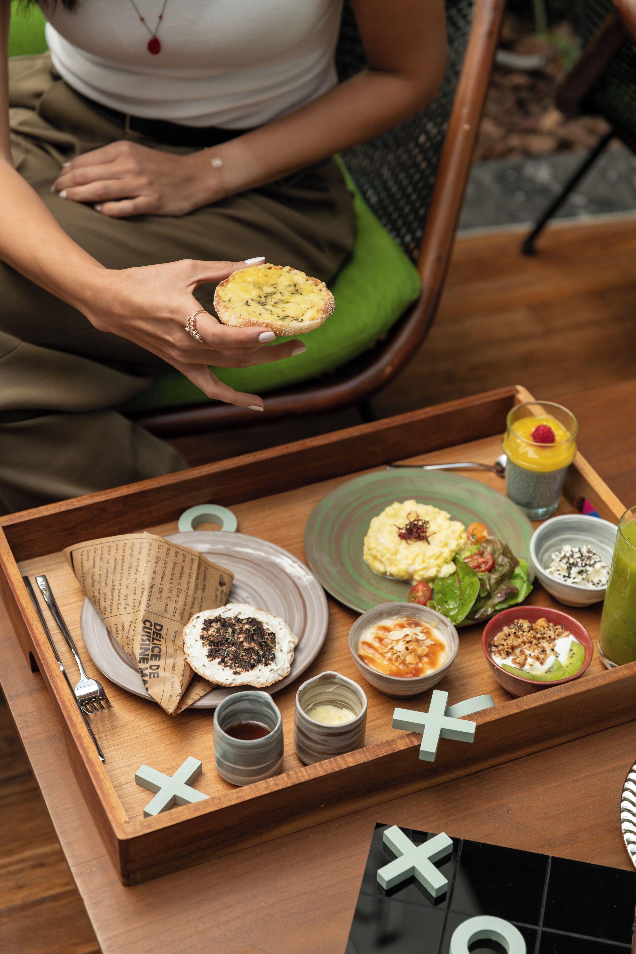 A wooden tray with various food items and a drink, placed on a table.