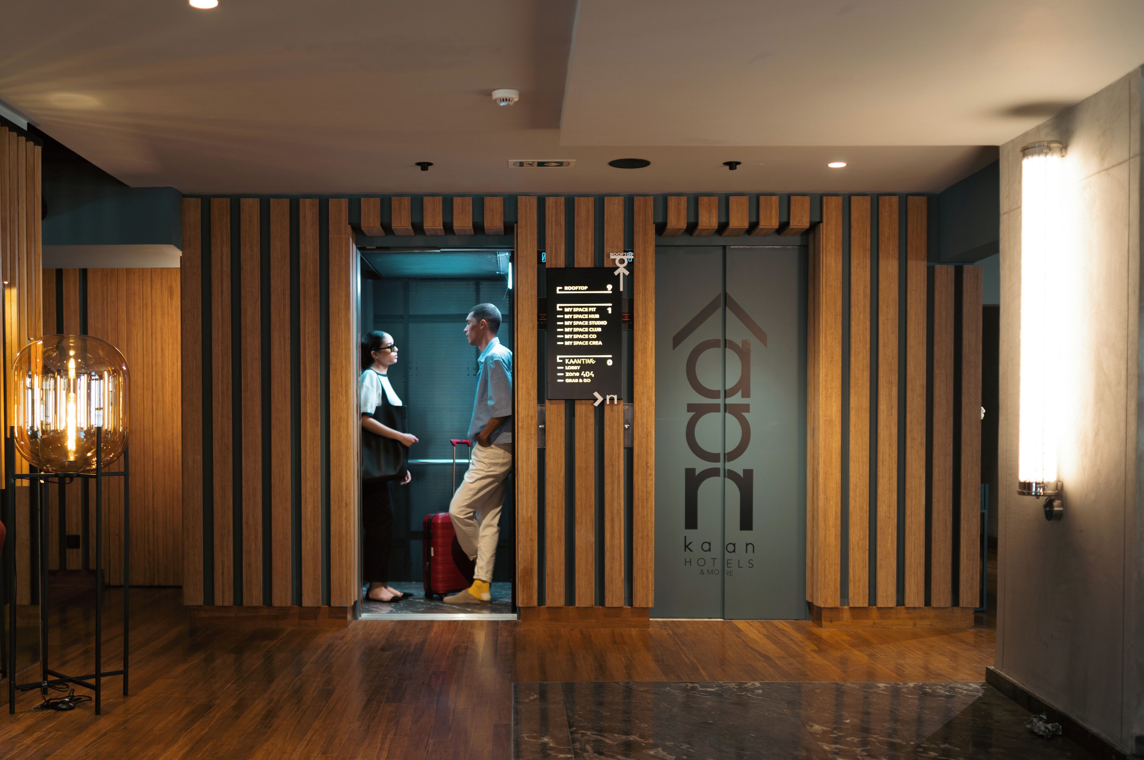 A hotel reception area with a wooden panel design, a reception desk, and a directional sign.