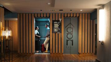 A hotel reception area with a wooden panel design, a reception desk, and a directional sign.