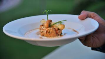 A white plate with a food dish, held by a hand.