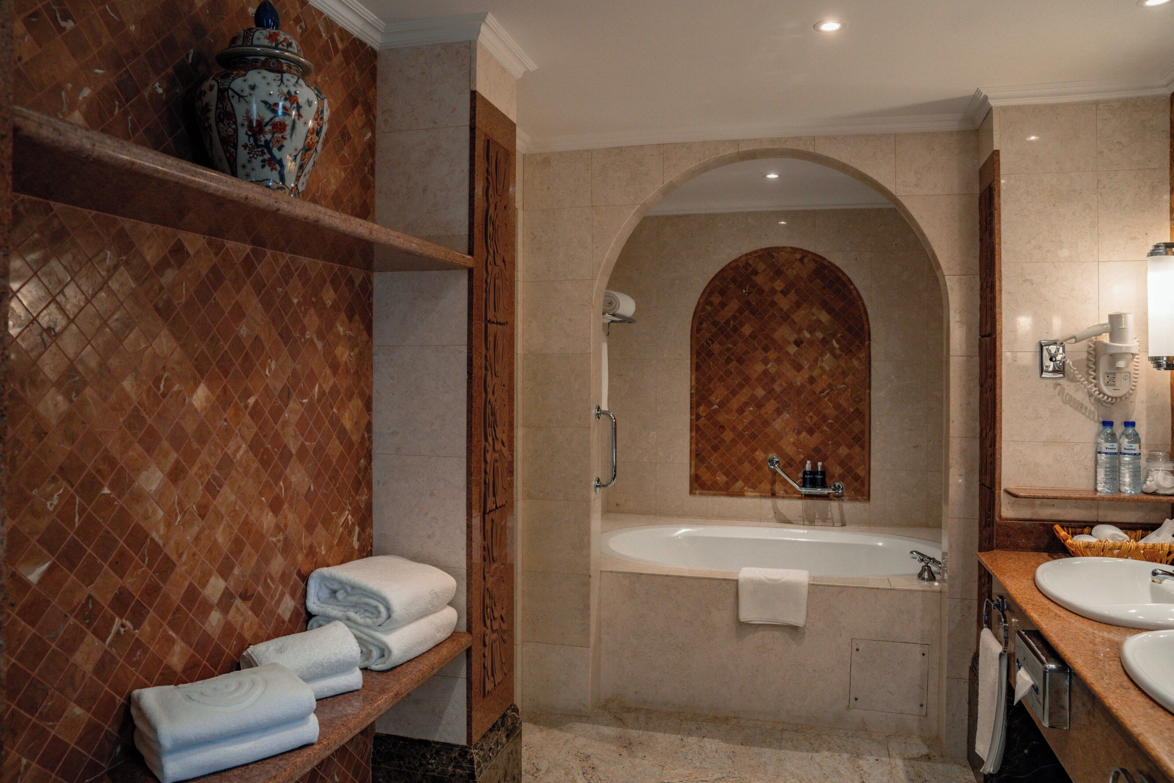 A bathroom with a bathtub, a vanity with a sink, and a towel rack with folded towels.