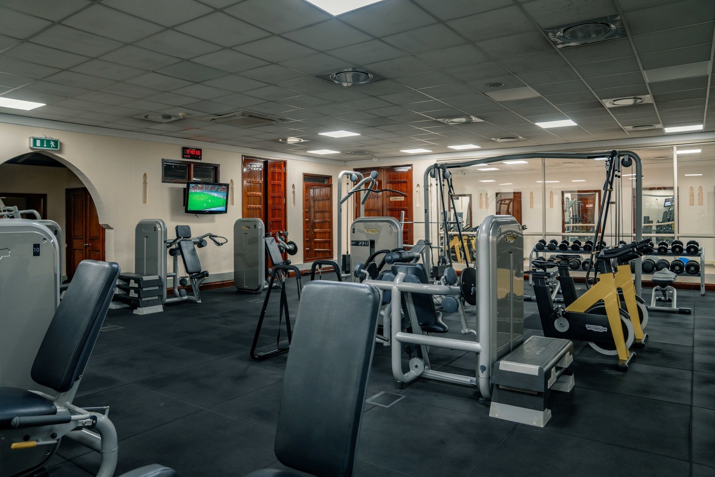 A gym with various exercise equipment, a television, and a mirror.