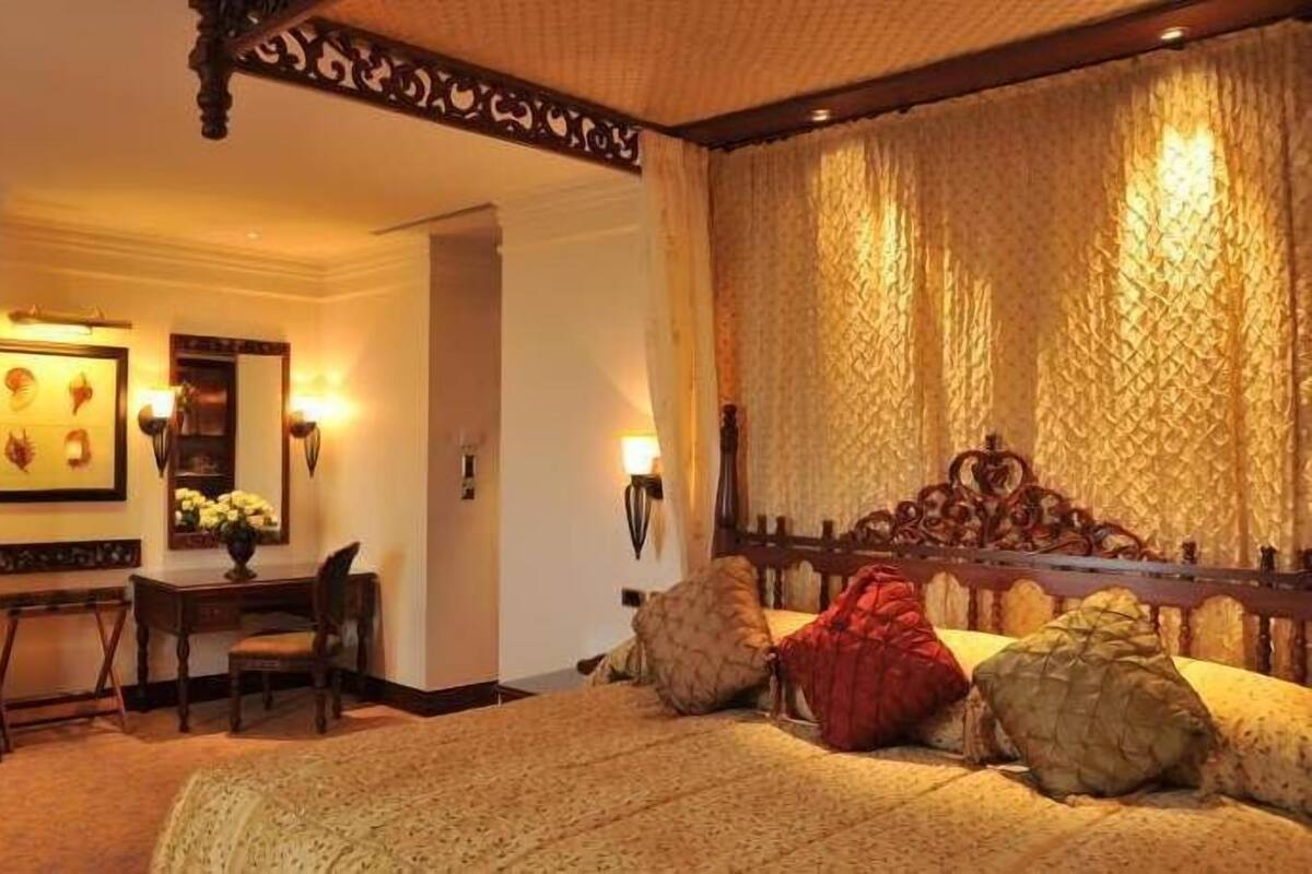 Ein Schlafzimmer mit einem großen Bett, einem Schreibtisch mit Stuhl, einem Spiegel und Wandleuchten.