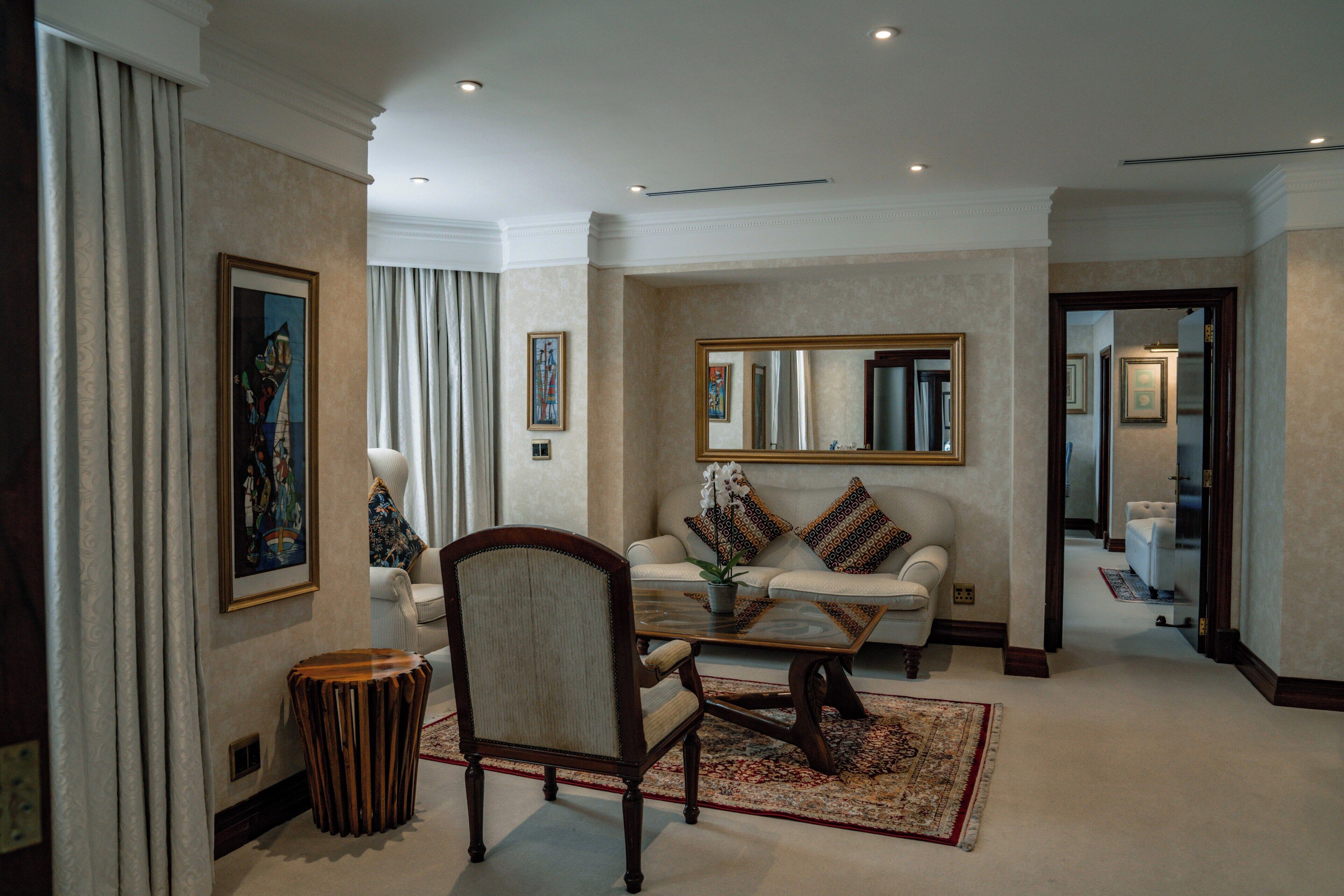 Un salón amplio con sofá, sillones, una mesa de centro y un espejo decorativo.