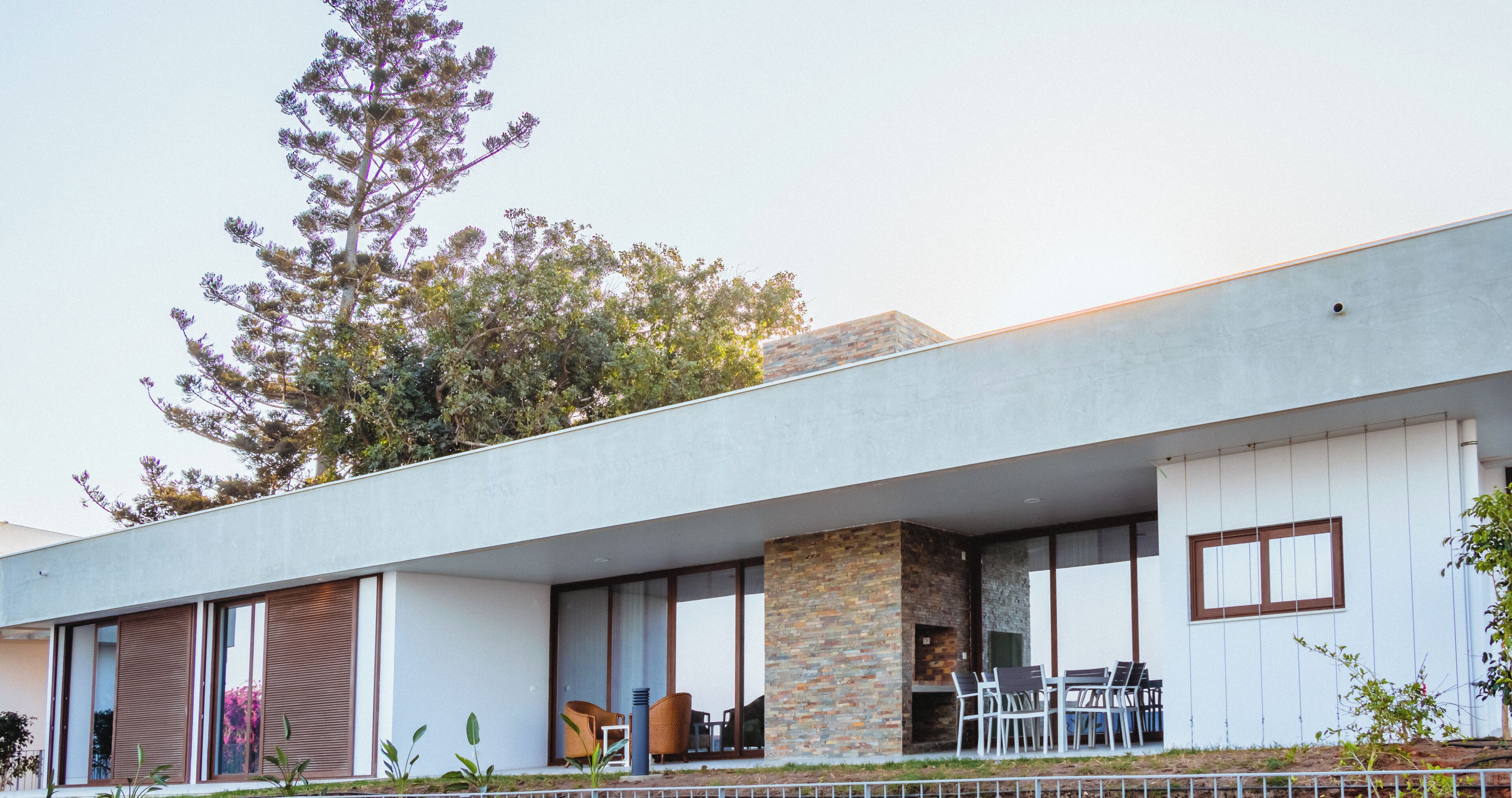 Una casa moderna con tetto piatto, ampie finestre e una zona patio con mobili da esterno.